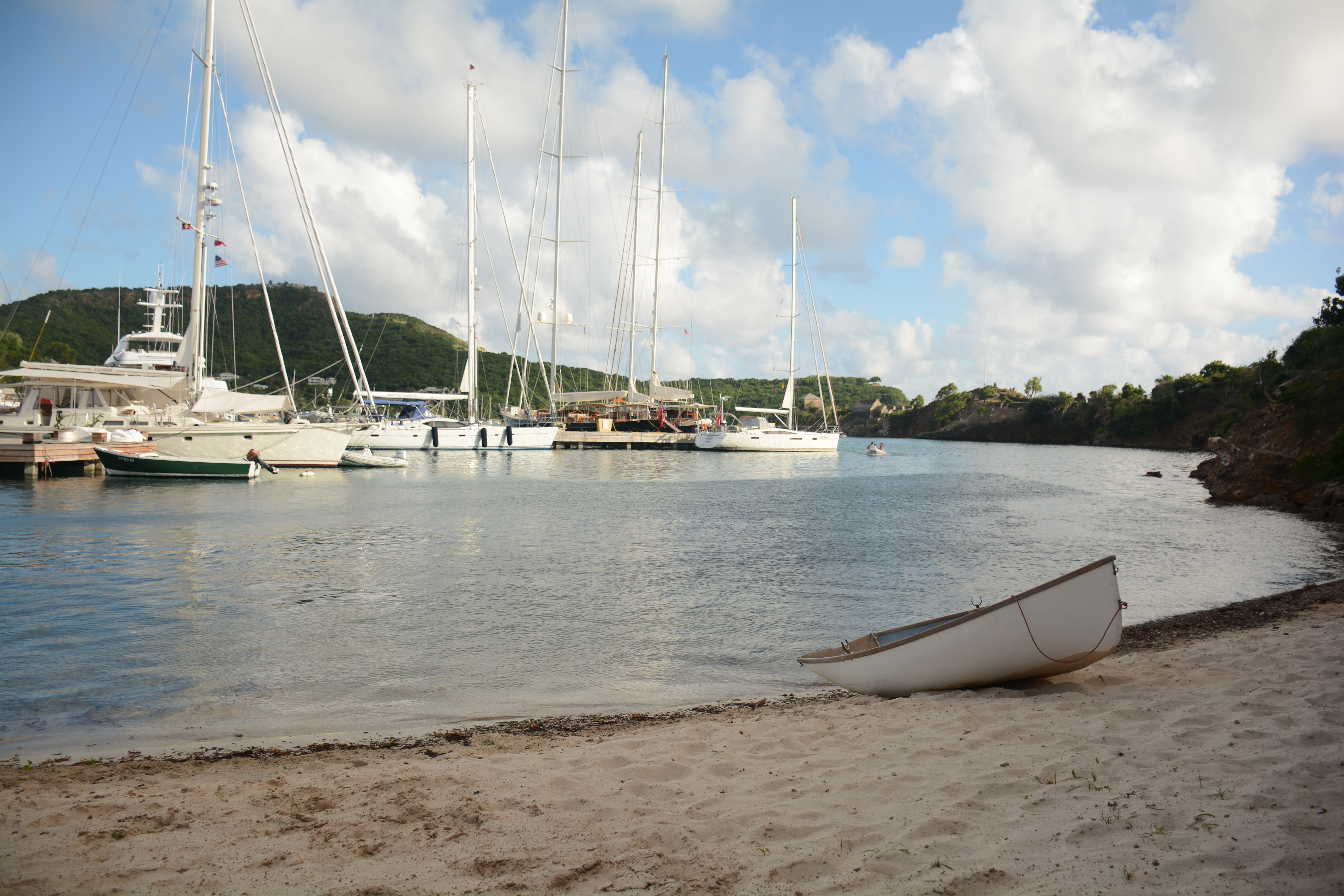 image of beach with sailboats docked in the background.